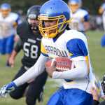 Photo by Rashah McChesney/Peninsula Clarion  Barrow Whaler Tony Dunbar nabs a first down before being taken out during a game against the Nikiski Bulldogs Friday September 26, 2014 in Nikiski, Alaska.
