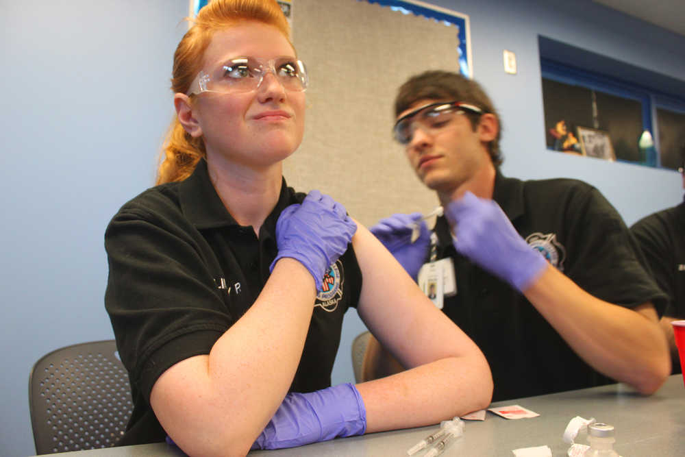 Photo by Kelly Sullivan/ Peninsula Clarion Lindey Pabst looks away as classmate Brooks Simmons practices an intramuscular injection on her, Monday, September 29, 2014, at the Kenai Peninsula College in Soldotna, Alaska.