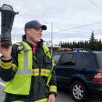 Photo by Rashah McChesney/Peninsula Clarion  Kenai firefighter Justin Horton waves a boot in the air for drivers along the Kenai Spur Highway Friday October 17, 2014 in Kenai, Alaska.  Several off-duty firefighters stood near the intersection of Bridge Access Road and the highway soliciting donations for the Muscular Dystrophy Association.