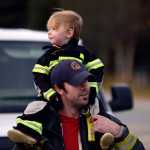 Photo by Rashah McChesney/Peninsula Clarion Kenai Firefighter Abe Porter holds his daughter Eden Porter, 2, as the two collect donations for the Muscular Dystrophy Association during a one-day fill-the-boot campaign Friday October 17, 2014 in Kenai, Alaska.