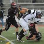 Nikiski's Christian Riddall (7) runs through a pair of Eielson defenders.  Photo for the Clarion by Michael Dinneen
