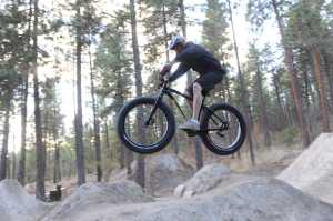 In this Oct. 21, 2014 photo, Ruk Kuchenbecker takes some jumps at the Beacon Hill jumps at Camp Sekani, in Spokane, Wash. The fat bike - a seemingly typical mountain bike frame with tires ranging from 3.7 to 4.8 inches wide - owes its origin to Fairbanks, Alaska. (AP Photo/The Spokesman-Review, Jesse Tinsley)