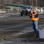 Photo by Rashah McChesney/Peninsula Clarion  A customer waits to leave the parking lot of Charlie's Pizza as Alaska Department of Transportation Station Manager Brian Gabriel, scrapes drilling mud from the Kenai Spur Highway on Tuesday Dec. 9, 2014 in Nikiski, Alaska. The slick mud coated a portion of the road after an early-morning spill of the waste. Representatives from the Alaska Department of Environmental Conservation and the AIMM Technologies Inc., said the waste was not hazardous.