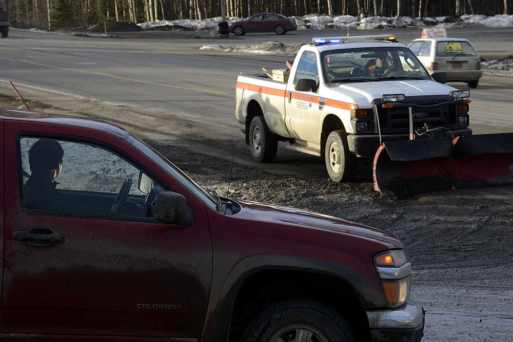 Photo by Rashah McChesney/Peninsula Clarion  Brian Gabriel, Department of Transportation Station Manager, works to scrape spilled drilling mud from a portion of the Kenai Spur Highway on Tuesday Dec. 9, 2014 near Mile 26 and Halliburton Road in Nikiski, Alaska.