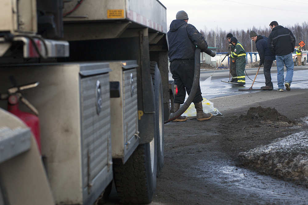 Photo by Rashah McChesney/Peninsula Clarion  A crew works to clean spilled drilling mud from the Kenai Spur Highway on Tuesday Dec. 9, 2014 in Nikiski, Alaska.