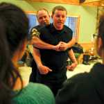 Photo by Rashah McChesney/Peninsula Clarion  Kenai police officers Jay Sjogren and Alex Prins demonstrate manuevers to escape an attacker during a Teens on Target self defense class on Thursday Dec. 11, 2014 in Kenai, Alaska.