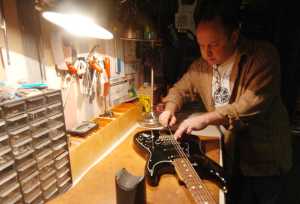 Photo by Kelly Sullivan/ Peninsula Clarion Dustin Aaronson, owner of Old Town Music, works on adjusting the intonation on an American made electric guitar Tuesday, Dec. 16, 2014, in Kenai, Alaska. Intonation affects sound quality throughout the entire instrument, and while the technique is generally formulaic, sometimes rules are broken to ensure individual instruments have been properly tuned, Aaronson said.