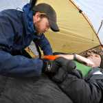 ADVANCE FOR WEEKEND EDITIONS, JAN. 10-11 - In this photo taken on Dec. 20, 2014, Oregon State student Ben Church, left, examines fellow student Teddy White, while under a tent during a heavy rain as part of their wilderness first responders class final exam in Corvallis, Ore.  Church was checking White's heart rate and respiration while White was pretending to have broken his arm on a hiking trip. (AP Photo/The Corvallis Gazette-Times, Andy Cripe)