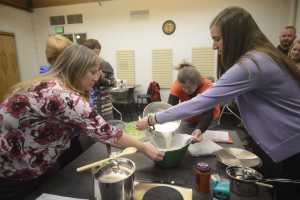 Photo by Kelly Sullivan/ Peninsula Clarion Beth Lyons and Anne McCabe help Amy Lou Pascucci during one of the beginning steps of making Paneer Tuesday, Feb. 10, 2015, at the Kenai Community Library in Kenai, Alaska. Lyons said, in the past, she has visisted the library mainly so she and her children could check out reading materials. More recently she, and she believes the wider community, come for classes such as Pascucci's cheese-making workshop, and as a place to congregate.