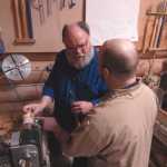 Sterling Rasumussen teaches Lee Halstead how to turn a birch goblet on an electric lathe at a Kenai Peninsula Woodturner's meeting at the "3 Guys, No Wood" workshop on Saturday, Feb. 14.