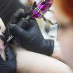 Photo by Kelly Sullivan/ Peninsula Clarion Lori Salyers, who is getting a black and white image of a cat sitting beside a tombstone just below her shoulder, said the tattoo was inspired by her favorite holiday, which is Halloween, Saturday, March 14, 2015, at Ink Works in Kenai, Alaska.