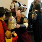 Ben Boettger/Peninsula Clarion David Ekholm, known as Nikor from the Isle of Oaks, lets a visitor try on his helm during the Society for Creative Anachronisms Newcomers Feast at the Soldotna Public Library on Saturday, March 14.