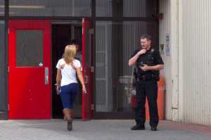 Photo by Rashah McChesney/Peninsula Clarion  An officer from the Kenai Police Department talks to a woman as she enters Kenai Central High School on Tuesday April 14, 2015 in Kenai, Alaska. Officers responded to the school after a student received a threatening text and the school was put into lockdown mode.