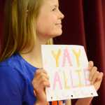 Photo by Kelly Sullivan/ Peninsula Clarion Kenai Central senior Allie Ostrander holds up a sign handmade by a friend for encouragement right before signing a National Letter of Intent to run at Idaho's Boise State University Wednesday, April 15, 2015, at Kenai Central High School in Kenai, Alaska.
