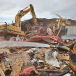 Photo by Rashah McChesney/Peninsula Clarion Emmanual Middleton, of S&R Enterprises, hoses down debris to keep it from getting into the air on Monday April 20, 2015 in  Kenai, Alaska.  Workers are demolishing the Kenaitze Indian Tribe's Tyotka's Elder Center building at the corner of Mission Avenue and Upland Drive on Monday April 20, 2015 in  Kenai, Alaska. The tribe made a decision to replace the building after structural damage requiring extensive repairs was discovered in 2014, according to a media release.