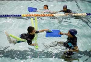 Young swimmers and their teachers swim in a pool during a swim lesson in the Bronx borough of New York, Wednesday, April 15, 2015. They are in swim swim swim I SAY, one of 65 programs around the country to receive grants from the nonprofit Autism Speaks to provide the personal attention and patience if often takes to help children on the autism spectrum learn to swim. Many are prone to wander and many are drawn to water.(AP Photo/Seth Wenig)