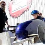 Ben Boettger/Peninsula Clarion Organizer Scott Hamann (left) looks on while champion racer Wyatt Wasczak is placed on the starting ramp during the Kenai Rotary Soapbox Derby in the parking lot of Kenai's Challenger Learning Center.