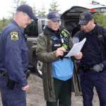 Photo by Dan Balmer/Peninsula Clarion Kenai Police Sgts. Scott McBride (left) and Jay Sjogren review a map with Lisa Jaegar from the Mat-Su Search and Rescue Dogs on Borgen Av. Monday in North Kenai. Two rescue dog teams along with agents with the FBI are searching the wooded area north of Wildwood Correctional Facility for a Kenai family of four missing since May 27.
