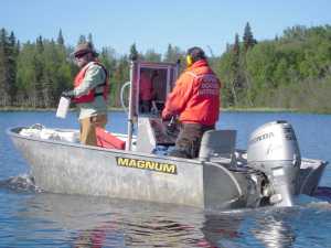 John Morton/Kenai Wildlife Refuge Andrew Skibo (left) of chemical manufacturer SePRO oversees application of the herbicide Diquat at Daniels Lake, in a boat piloted by Kenai Wildlife Refuge Biologist Todd Eskelin (right) on Tuesday, June 3 2014. After being mixed with lake water, liquid Diquat enters the lake from a spray-hose on the rear of the boat.