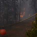 Photo by Kelly Sullivan/ Peninsula Clarion Bureau of Land Management Alaska Fire Service contracted planes that dropped fire retardant adjacent to homes that were threatened by the Card Street Fire Monday, June 15, 2015, in Sterling, Alaska. Jerry Millett who lives on Cottontree Lane went back to see if his property had suffered any damage from the fire around 4 p.m. All structures were still standing, and he said he was fine with the red retardant being everywhere as long as nothing was burned.