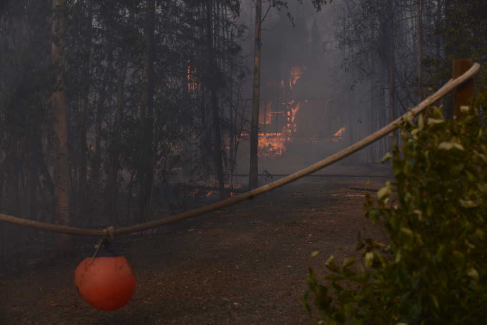 Photo by Kelly Sullivan/ Peninsula Clarion Bureau of Land Management Alaska Fire Service contracted planes that dropped fire retardant adjacent to homes that were threatened by the Card Street Fire Monday, June 15, 2015, in Sterling, Alaska. Jerry Millett who lives on Cottontree Lane went back to see if his property had suffered any damage from the fire around 4 p.m. All structures were still standing, and he said he was fine with the red retardant being everywhere as long as nothing was burned.