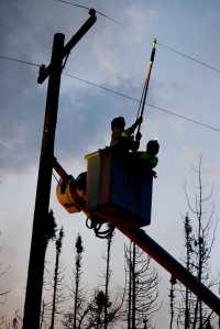 Photo by Rashah McChesney/Peninsula Clarion  HEA linemen work on the power lines in the early morning hours as spot fires burn close by near the Kenai Keys subdivision where the Card Street fire has burned thousands of acres and several structures.