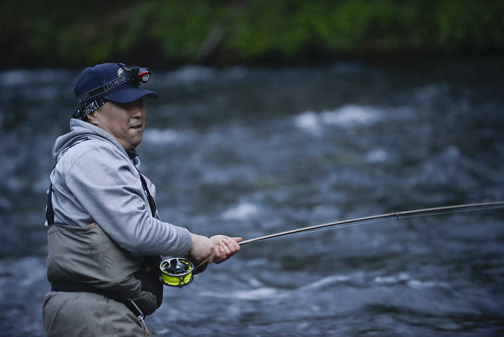 Photo by Rashah McChesney/Peninsula Clarion John Mun, of Anchorage, reels a fish in during the Russian River sockeye salmon opener on Thursday June 11, 2015 near Cooper Landing, Alaska.