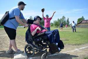 Photo by Rashah McChensey/Peninsula Clarion Isaac Cryer helps Chuck Davis, both of Soldotna, round third base during the annual World Series of Baseball event for community members with developmental disabilities on Friday June 19, 2015 in Soldotna, Alaska.