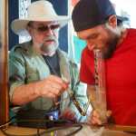Kirk Daman, of Homer, (left) helps Logan Jensen, of Homer, (right) sample a cannabis product on Saturday at the Green Rush Events Clubhouse in Kenai. Photo by Megan Pacer/Peninsula Clarion