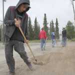 Ben Boettger/Peninsula Clarion Volunteer Max Cox rakes a patch of dirt between Kenai Central High School and Lawton Drive during a beautification project led by Eagle Scout candidate Brett Brown on Tuesday, July 21.