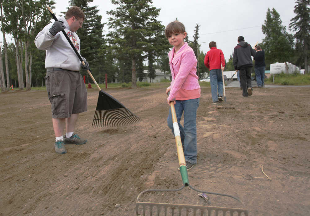 Ben Boettger/Peninsula Clarion During a beautification project led by Eagle Scout candidate Brett Brown (left), volunteer Melody Cox (right) rakes a patch of dirt between Kenai Central High School and Lawton Drive on Tuesday, July 21.