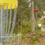 Ben Boettger/Peninsula Clarion Glenn Yamada throws a frisbee at a goal basket during a disc golf tournament at Tsalteshi Trail on Saturday July 25.