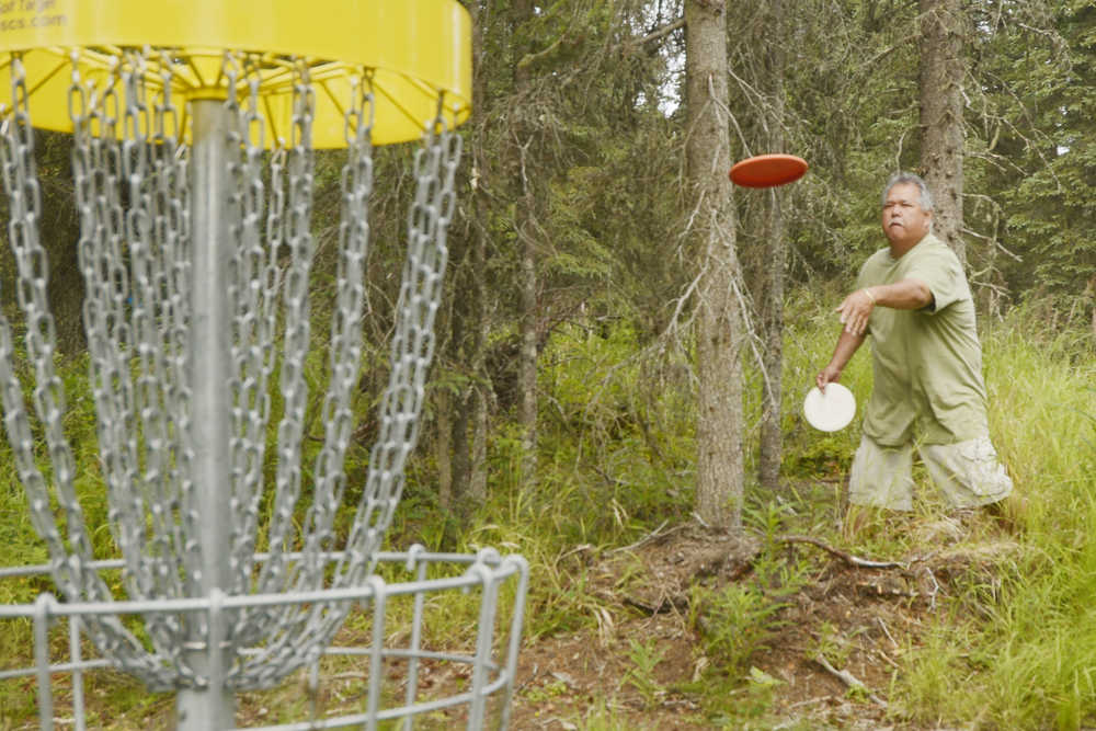 Ben Boettger/Peninsula Clarion Glenn Yamada throws a frisbee at a goal basket during a disc golf tournament at Tsalteshi Trail on Saturday July 25.