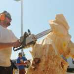 Megan Pacer/Peninsula Clarion Jeff Eshom, a chainsaw sculptor at Soldotna's Town of Living Trees, works on a carving of a moose during the Sawfest Chainsaw Carving Competition in Centennial Park on Friday, July 25.