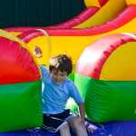 Photo by Megan Pacer/Peninsula Clarion Reece Solomon, 7, hops down from a bouncy slide at Salmonfest on Friday July 31, 2015 in Ninilchik, Alaska.
