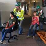 Photo by Megan Pacer/Peninsula Clarion Leah Vik (left) and Daughn Carpenter (right) wheel volunteers posing as victims out of an earthquake simulation held Saturday Aug. 8, 2015, at Soldotna Prep School in Soldotna, Alaska. This summer's volunteers for Community Emergency Response Team training were made up mostly of Girl Scouts and Boy Scouts.