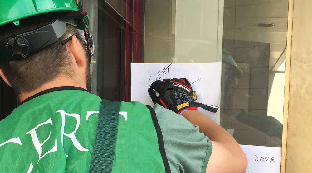 Photo by Megan Pacer/Peninsula Clarion Jeremiah Millette, a member of the Kenai Peninsula Borough's most recent Community Emergency Response Team class, labels the front door of Soldotna Prep as he and other classmates begin an earthquake simulation at the end of the course. The exercise was held on Saturday, Aug. 8, 2015 at Soldotna Prep School in Soldotna, Alaska.