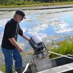 Photo by Megan Pacer/Peninsula Clarion Sterling resident Tommy Patterson inspects a boat motor belonging to his neighbor, Kenny Merkes, on Wednesday Aug. 12, 2015 on Moose River in Sterling, Alaska. Two men in a yellow canoe attempted to steal the motor from Patterson's property late Monday night.
