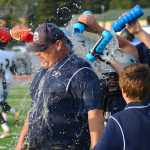 Ben Boettger/Peninsula Clarion Soldotna High School Football players douse their coach with water after a victory at Soldotna High School on Friday, August 14.