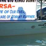 Photo by Rashah McChesney/Peninsula Clarion  Dave Athons, a board member for the Kenai Area Fisherman's Coalition, pilots a drift boat in front of Kenai River Sportfishing Association founder Bob Penney's home to protest Penney, the organization and it's annual Kenai River Classic fishing invitational on Wednesday August 19, 2015 in Soldotna, Alaska.