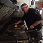 Photo by Kelly Sullivan/ Peninsula Clarion Richard Garrett prepares a burger for a customer Sunday, Aug. 23, 2015, at Garrett's Grill located inside The Place bar in Kenai, Alaska.