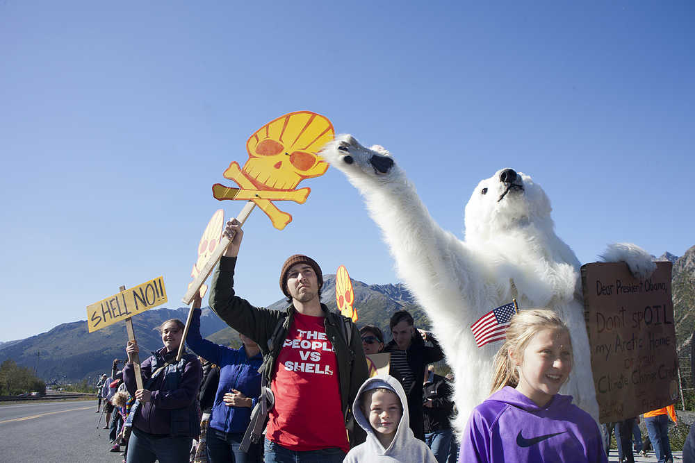 Photo by Rashah McChesney/Peninsula Clarion  Bryant DeHusson, of Anchorage, hands out free t-shirts bearing the slogan "The People vs. Shell" as hundreds crowd along the Seward Highway hoping to catch a glimpse of President Barack Obamaon Tuesday Setp. 1, 2015 during his visit to Seward, Alaska.