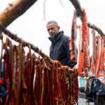 President Barack Obama looks at salmon being smoked while meeting with local fishermen and families on Kanakanak Beach, Wednesday, Sept. 2, 2015, in Dillingham, Alaska. Obama is on a historic three-day trip to Alaska aimed at showing solidarity with a state often overlooked by Washington, while using its glorious but changing landscape as an urgent call to action on climate change. (AP Photo/Andrew Harnik)