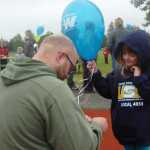 Photo by Megan Pacer/Peninsula Clarion Kenai resident Myles Sansotta (left) helps his 4-year-old daughter, Molli, tie a knot in the string of her balloon on Monday, Sept. 7, 2015 at the annual Labor Day Picnic at Kenai Central High School in Kenai, Alaska.