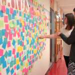 Photo by Megan Pacer/Peninsula Clarion Leslie Fazio (background) and Laura Beeson point out positive messages on the "Wall of Hope" they had high school students create as part of the new statewide Suicide Prevention Week, on Thursday, Sept. 10, 2015 at Kenai Central High School in Kenai, Alaska.
