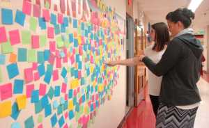 Photo by Megan Pacer/Peninsula Clarion Leslie Fazio (background) and Laura Beeson point out positive messages on the "Wall of Hope" they had high school students create as part of the new statewide Suicide Prevention Week, on Thursday, Sept. 10, 2015 at Kenai Central High School in Kenai, Alaska.