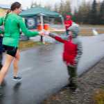 Photo by Rashah McChesney/Peninsula Clarion  Joann Jeplawy takes a cup of water from Samuel Anders at a relay station on the the Kenai River Marathon route along the Kenai Spur Highway on Sunday Sept. 26, 2015 in Kenai, Alaska. Jeplawy finished 18th out of the 97 runners in the half marathon race.
