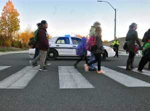 Jane Fellman (right), coordinator of the Safe Kids of the Kenai Peninsula Coalition, hands out string backpacks at the annual walk to school event.