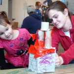 Ben Boettger/Peninsula Clarion Charlotte Wardas (left) and Sarah Gardner construct a house out of cardboard and duct tape during the Cardboard Challenge on Friday, Oct. 9 at the Soldotna Public Library.