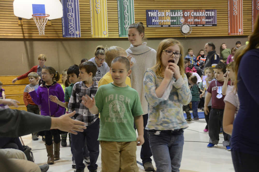Photo by Megan Pacer/Peninsula Clarion Daniel Carter, a fourth-grade student, reaches out to high-five a veteran at the close of a Veterans Day assembly on Wednesday, Nov. 11, 2015 at Nikiski North Star Elementary School in Nikiski, Alaska. It was the school's first Veterans Day event.
